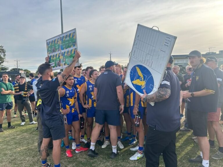 Aussie rules team strategising during game huddle.