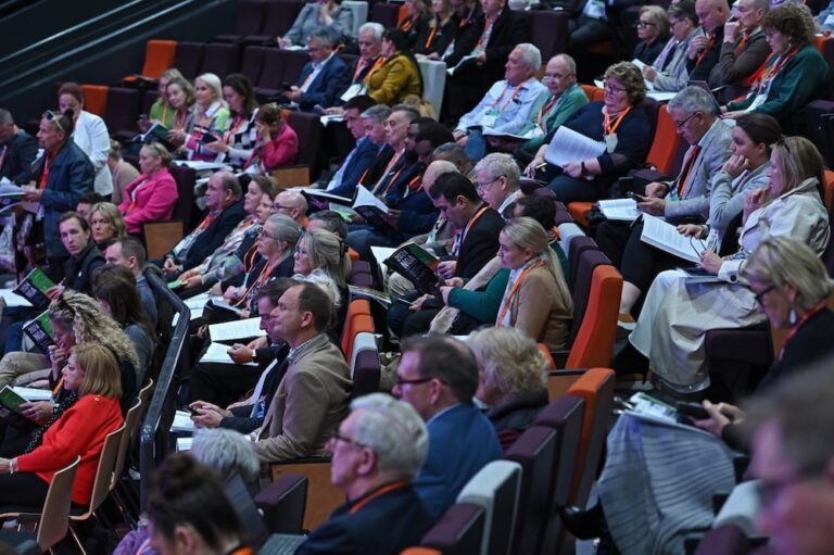 Audience attending a conference, taking notes.