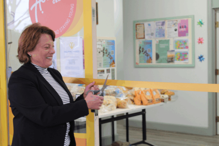 Woman cutting ribbon at community centre opening.