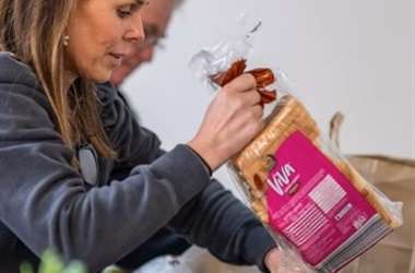 Woman unpacking groceries, holding bread.