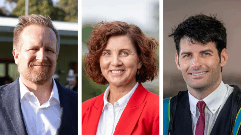 Three people smiling outdoors in professional attire.