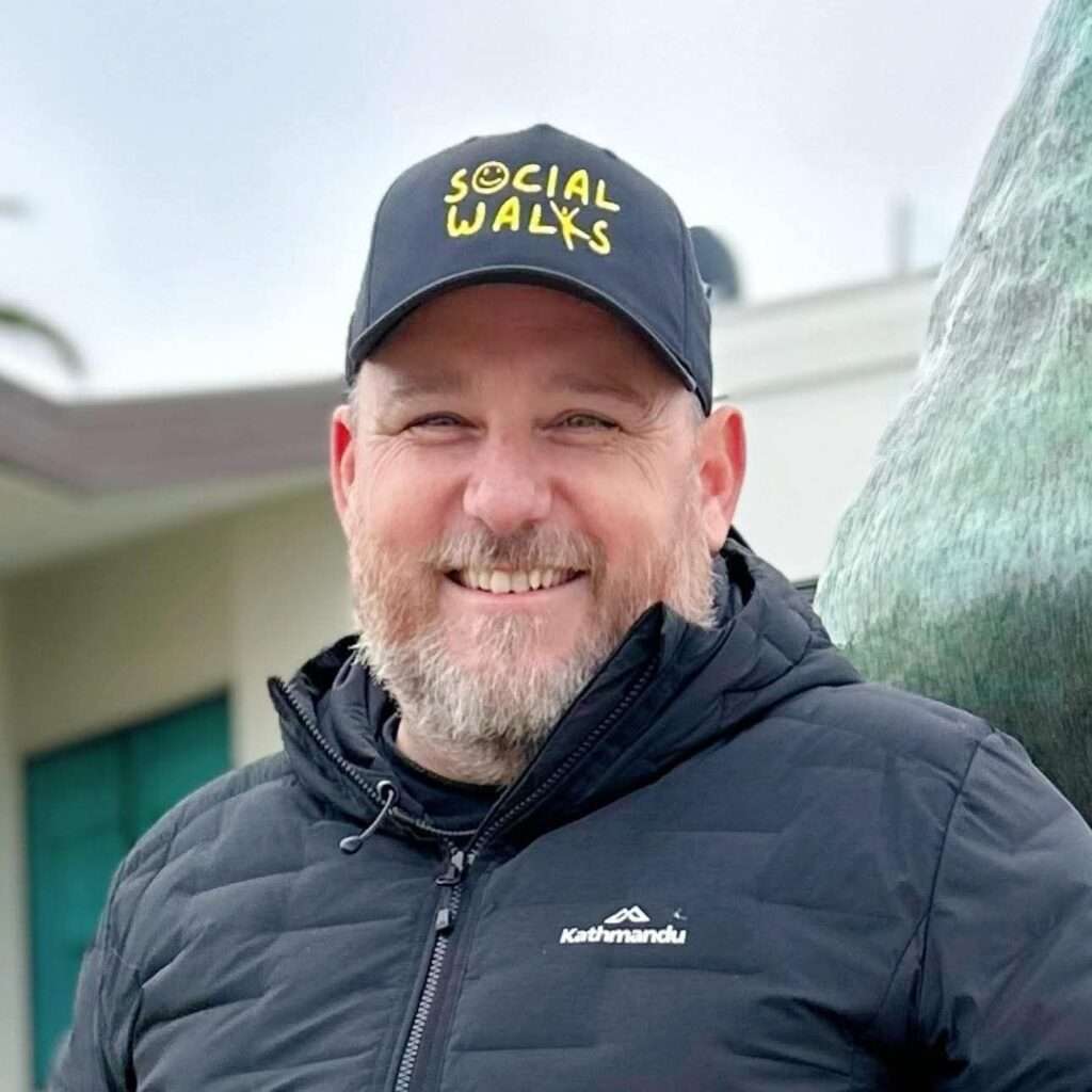 Man in Social Walks cap smiling outdoors.