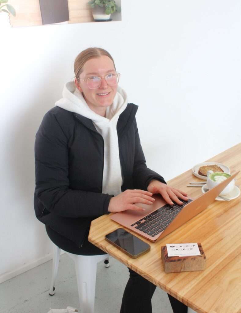 Person working on laptop in cafe with coffee.