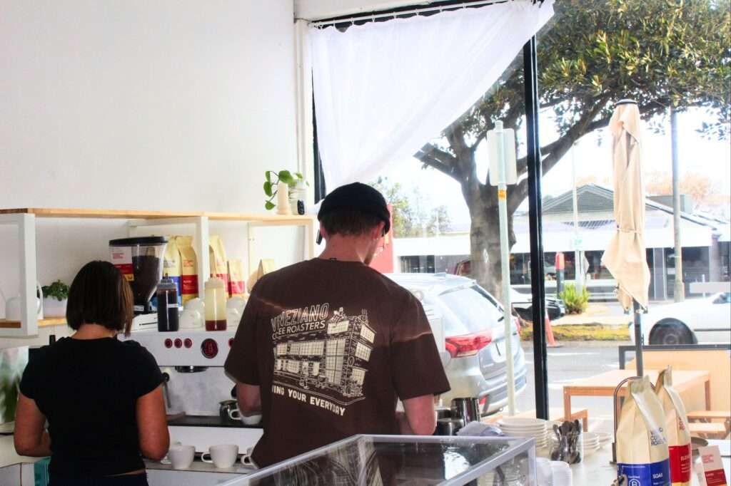 Baristas preparing coffee in a bright café.