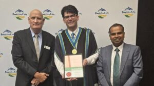 Three men at Frankston City event, one holds award.