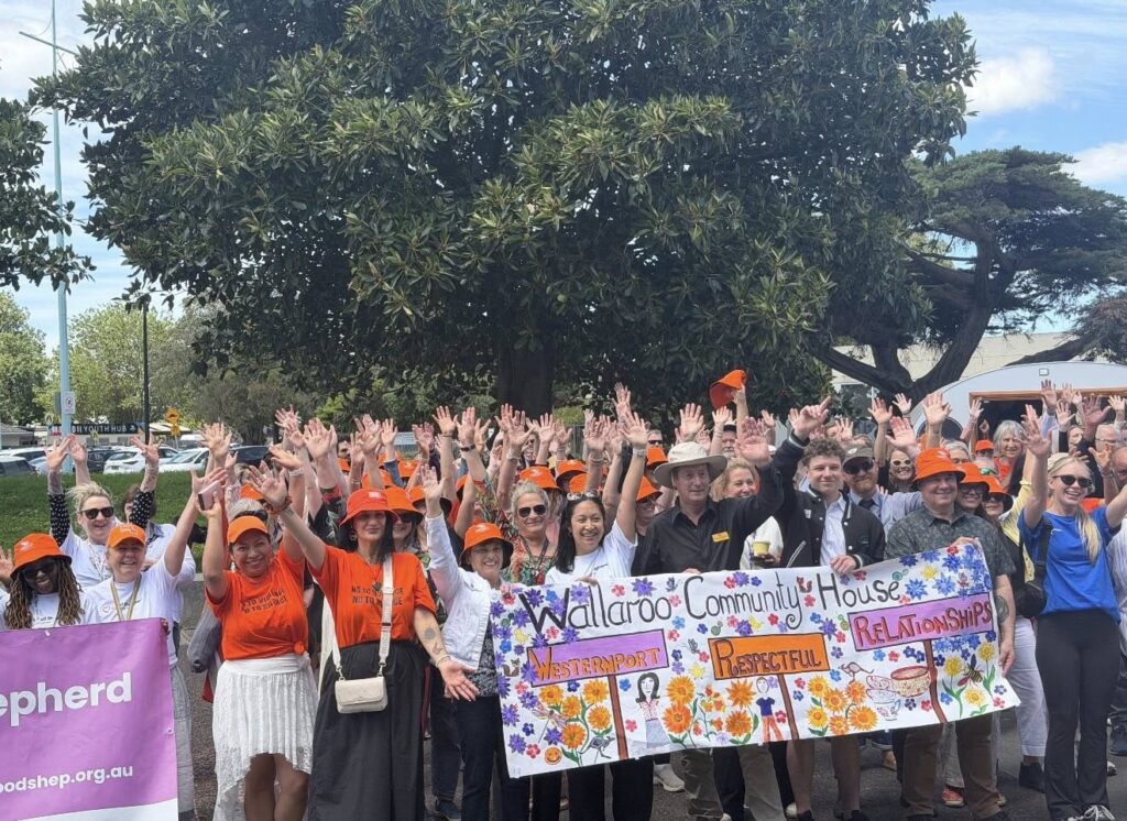 Community event with people holding banner and wearing orange hats.