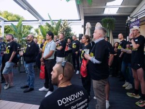 People gathering at outdoor event, holding drinks.
