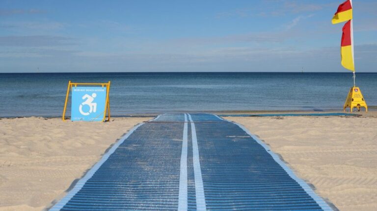 Accessible beach pathway with disability sign and flags.